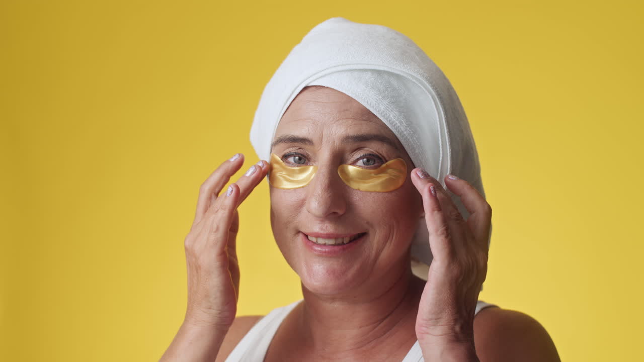 Caucasian Woman with Applied under Eyes Patches Smiling on Yellow Background
