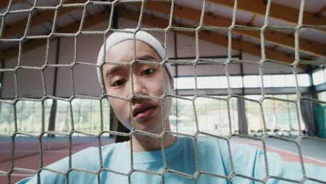 woman looking through tennis net