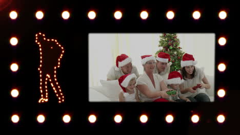 silueta de un hombre bailando mientras aparece un video que muestra a una familia con sombreros de santa