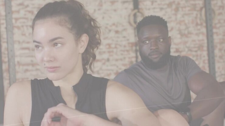 Vertical video: Woman adjusting zip top, man shifting in gym, fade showing rings, training prep