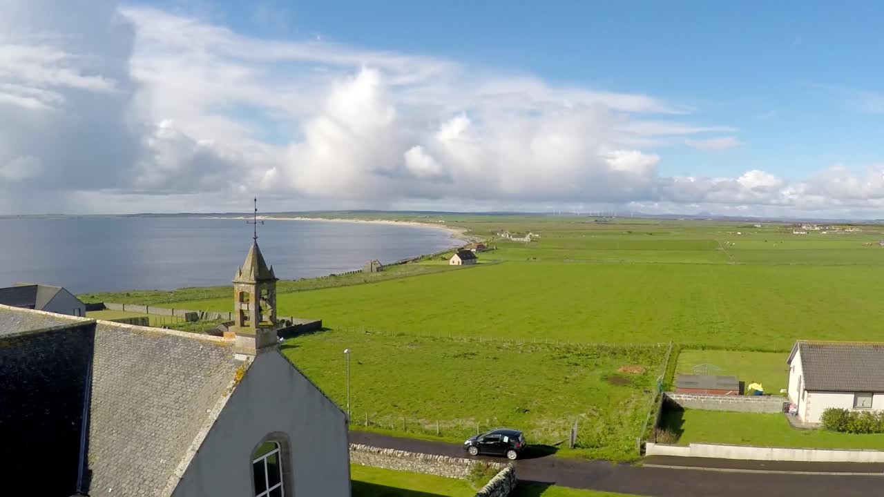 una toma aérea sobre una bonita iglesia a lo largo de la costa abandonada del norte de escocia