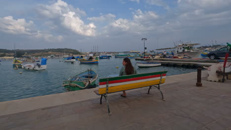 mujer sentada en el banco admirando los barcos flotando en la marina