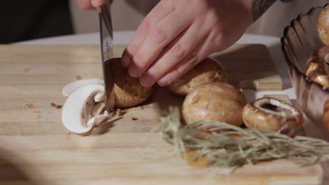 Die-Hand-Einer-Frau-Schneidet-Portobello-Pilze-Auf-Einem-Holzschneidebrett-Mit-Rosmarin