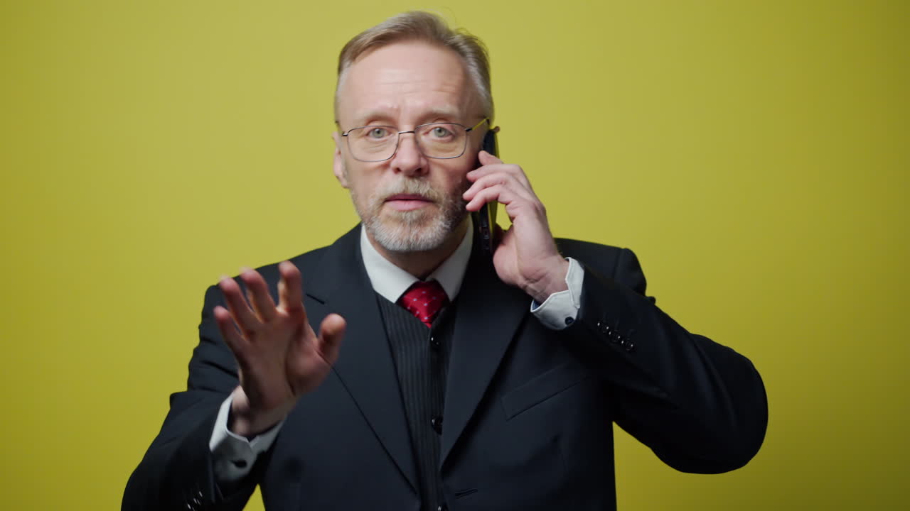 Uomo d'affari rilassato che parla al telefono. Elegante uomo d'affari che parla al telefono isolato su sfondo giallo.