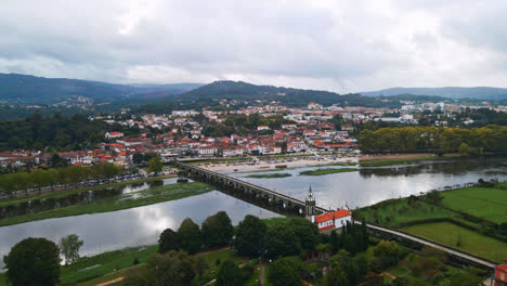 Stunning-aerial-4K-drone-footage-of-a-village---Ponte-de-Lima-in-Portugal-and-its-iconic-landmark---Stone-roman-bridge-crossing-over-the-Lima-River