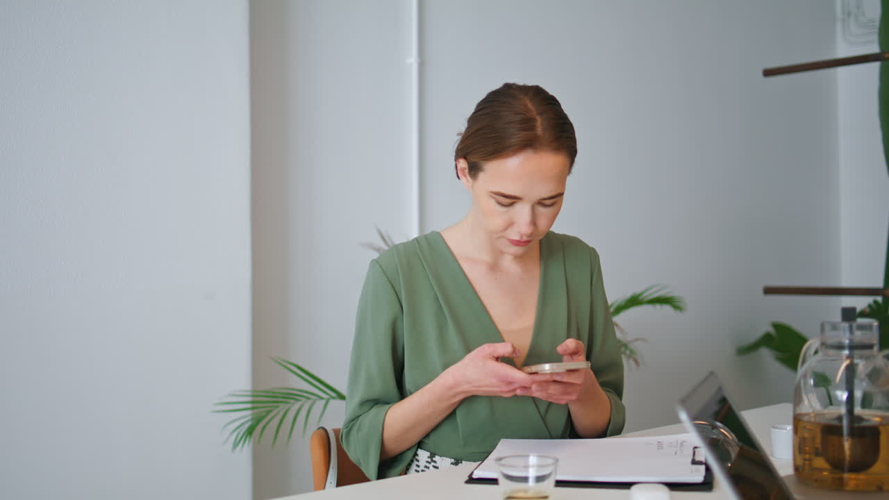 mujer de negocios enfocada enviando mensajes de texto al teléfono inteligente en el trabajo.