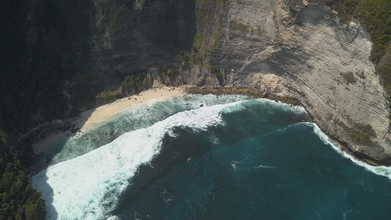 vista aérea del punto de acceso turístico kelingking beach en nusa penida, indonesia en un día soleado y con agua azul cristalina