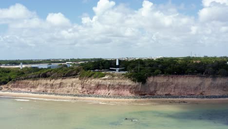 The-famous-tourist-destination-Cabo-Branco-Lighthouse-on-a-cliff-dolly-in-aerial-drone-wide-shot-in-the-tropical-beach-capital-city-of-Joao-Pessoa,-Paraiba,-Brazil-on-a-warm-sunny-summer-day