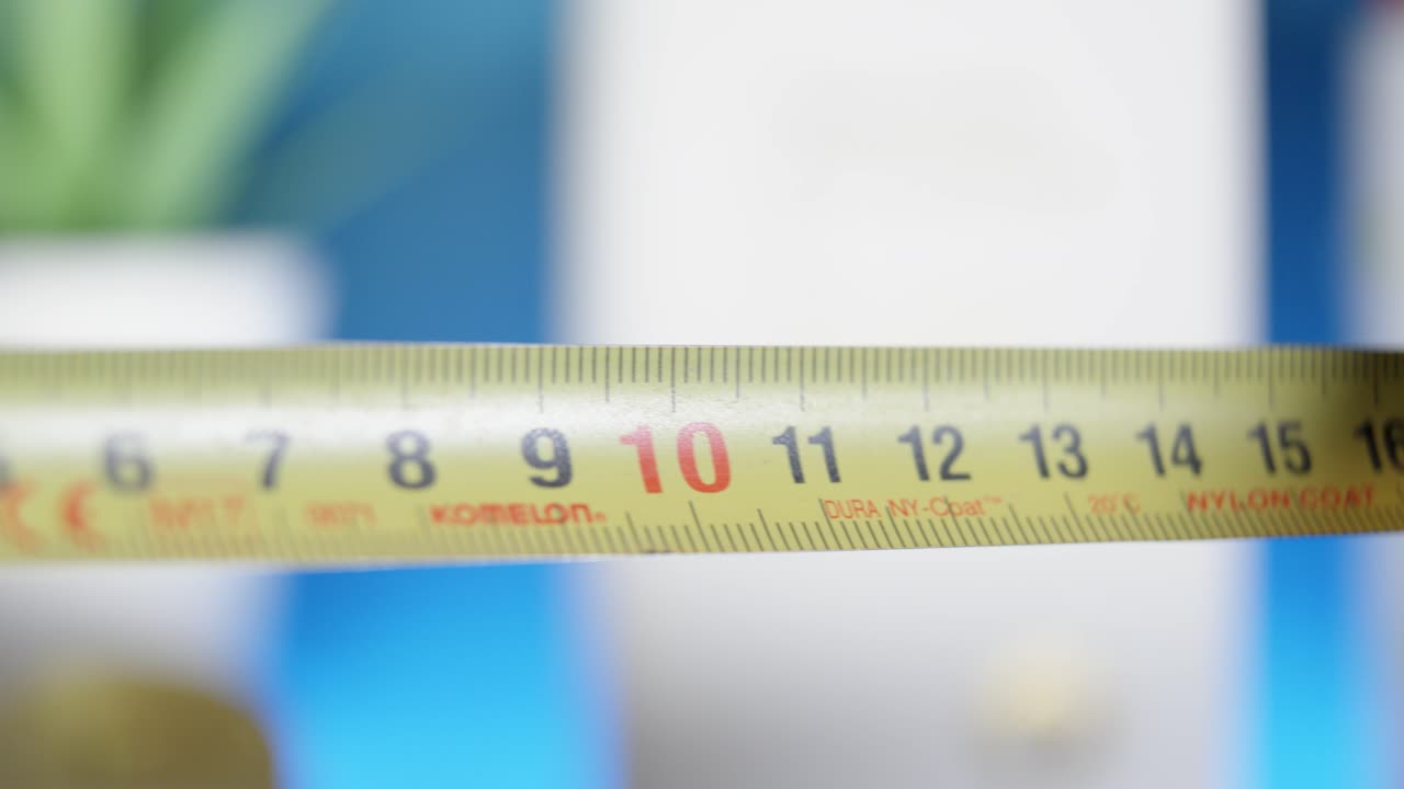 노란색 측정 테이프를 펴고 있는 사람의 클로즈업은 건축, diy 프로젝트 및 주택 개조에 필요한 이 필수적인 도구의 정밀성, 정확성 및 다재다능함을 강조합니다.