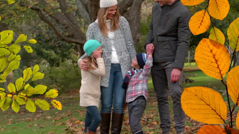 animation of autumn leaves falling over happy caucasian family in park