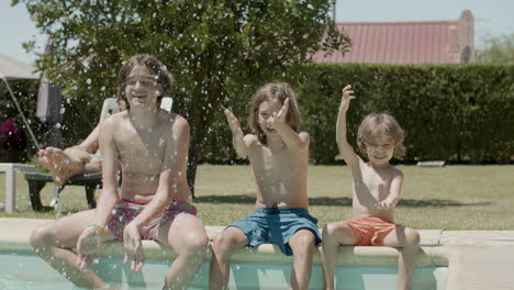 süße kinder sitzen am rand des schwimmbades und spritzen wasser