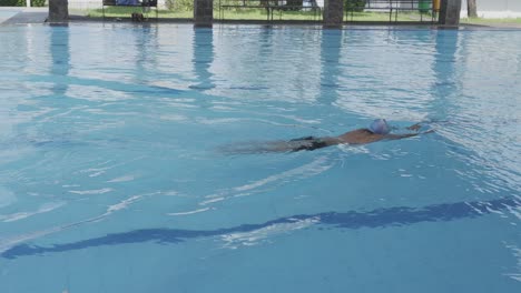 tracking shot of professional swimmer doing breaststroke swimming in the pool