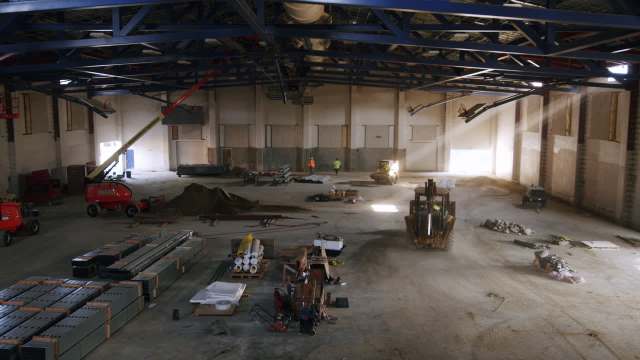 Large interior construction site with heavy machinery and workers