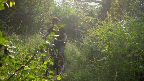 Junge-Mann-Radfahren-Im-Tiefen-Dschungel-Frontkamera-Sonnenstrahlen-Flairs-Filmisches-Offroad-radfahren-In-Der-Kamera