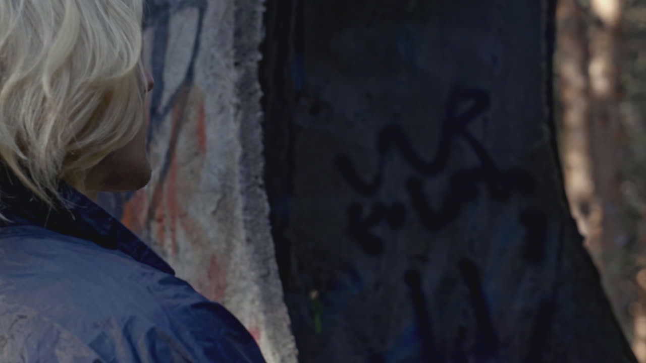 persona en el bosque con graffiti y equipo de campamento