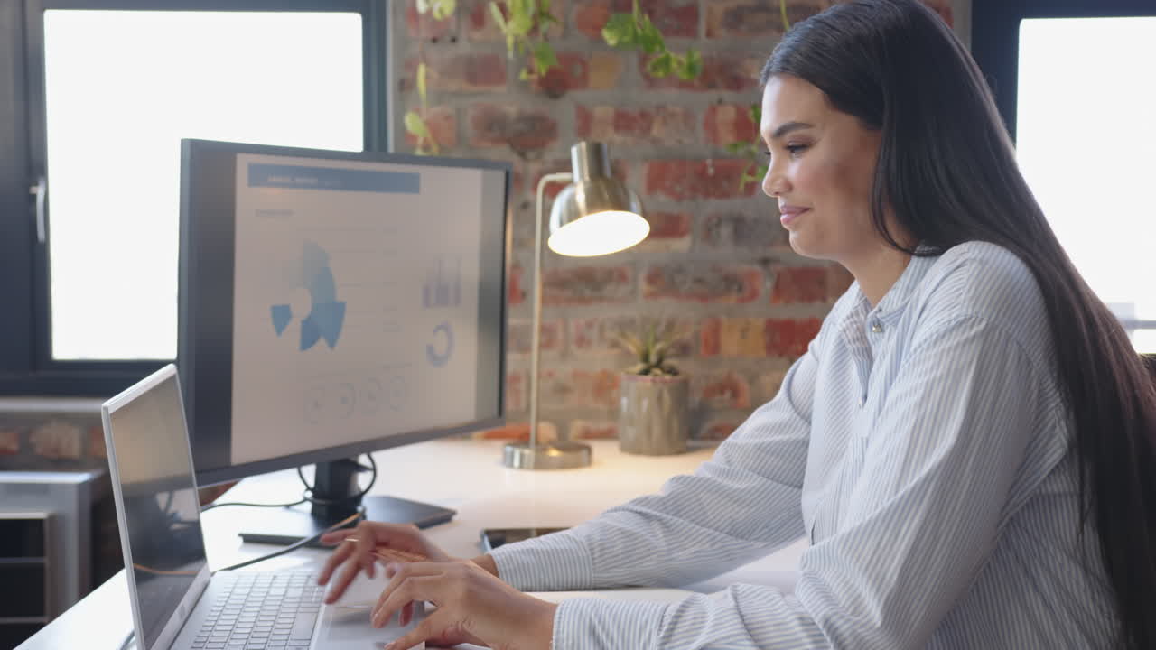 Working on laptop, woman analyzing data on computer screen in modern office