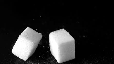 cubos de azúcar que caen sobre una superficie dura y negra