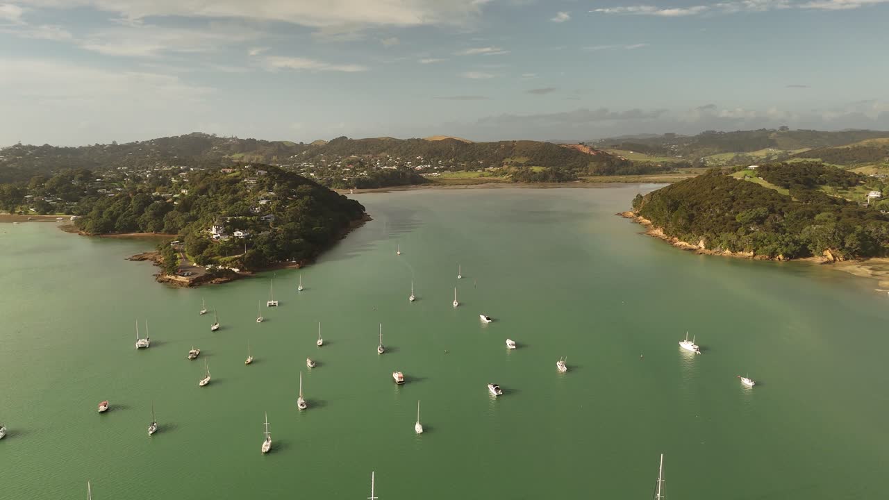 Sailboats and yachts moored in calm waters off Shelly Beach, Surfdale area, Waiheke Island, New Zealand. Aerial drone pov