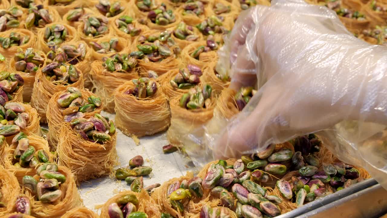 la mano del turista tomando knafeh (un postre de semolina y queso dulce hecho en el levante) de la estantería. primer plano. mercado de jerusalén (shuk). israel