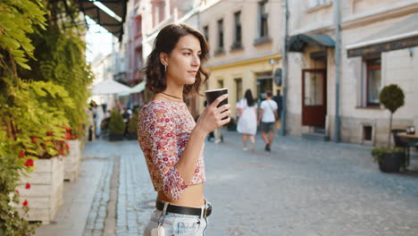 caucasian woman enjoying drinking morning coffee hot drink, relaxing, taking a break in city street