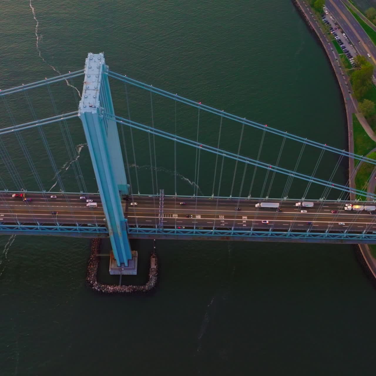 Rising high above the Whitestone Bridge. Numerous cars and lorries riding along the bridge and motorways of the island