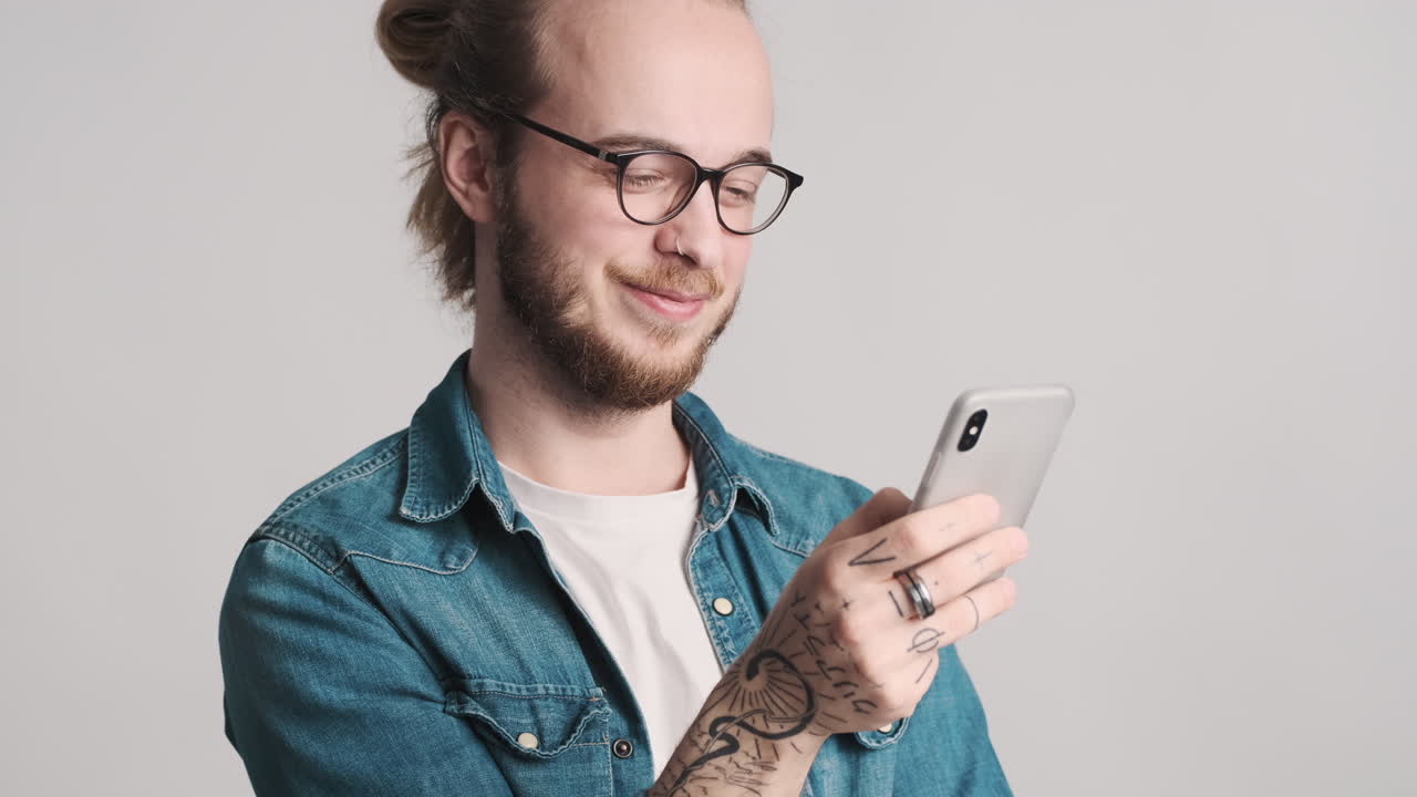 joven caucásico enviando mensajes de texto en el teléfono inteligente en la cámara.
