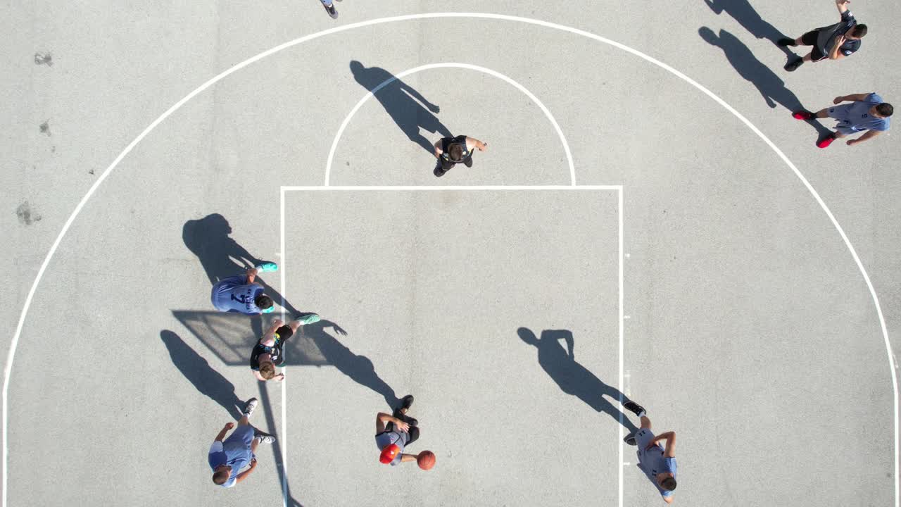 Top Down Aerial View of Men Playing Basketball on Outdoor Court on Sunny Day, High Angle Drone Shot