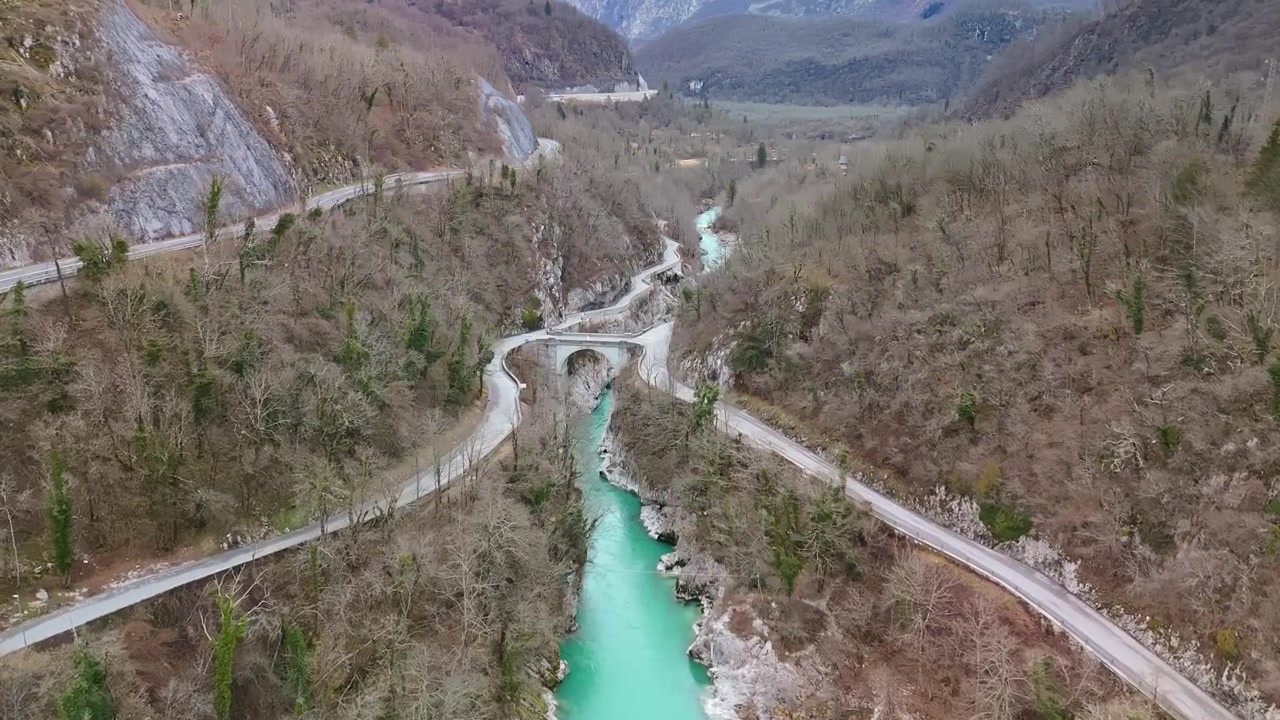 Kışın drone ile çekilen, Slovenya'nın Kobarid yakınlarındaki Soča Vadisi'nde, kış ormanı, kayalık geçit ve kıvrımlı dağ yolu ile Soča Nehri ve Napolyon Köprüsü.