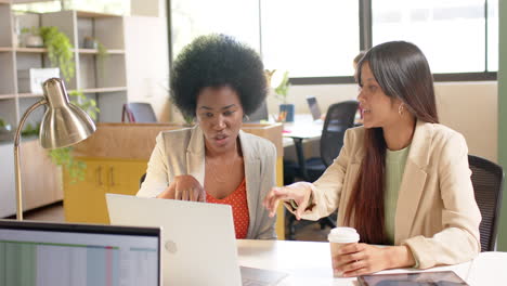 happy diverse female creative colleagues in discussion using laptop in office, slow motion
