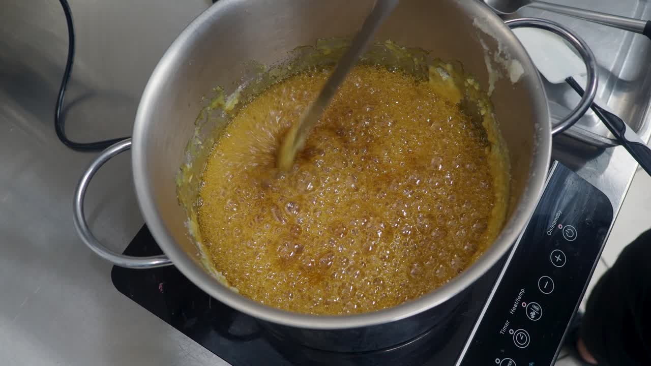 cuoco cucina burro salato caramello dessert , bollente, stir con spatola, caldo liscio cotto salata salata in padella d'acciaio sul fornello