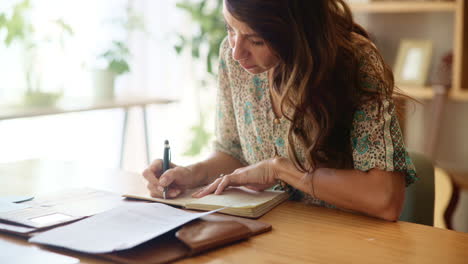 mujer escribiendo en un cuaderno en un escritorio