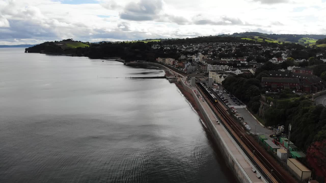Aerial view of a train at Dawlish station, located in Devon, England, a popular seaside resort town. Rising Shot