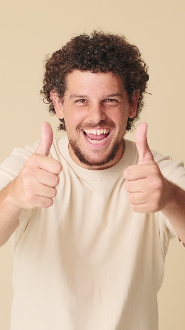 Giovane uomo con capelli ricci che sorride e fa il pollice in su