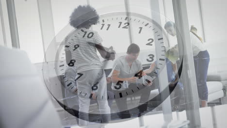 animation of ticking clock against team of diverse colleagues discussing together at office