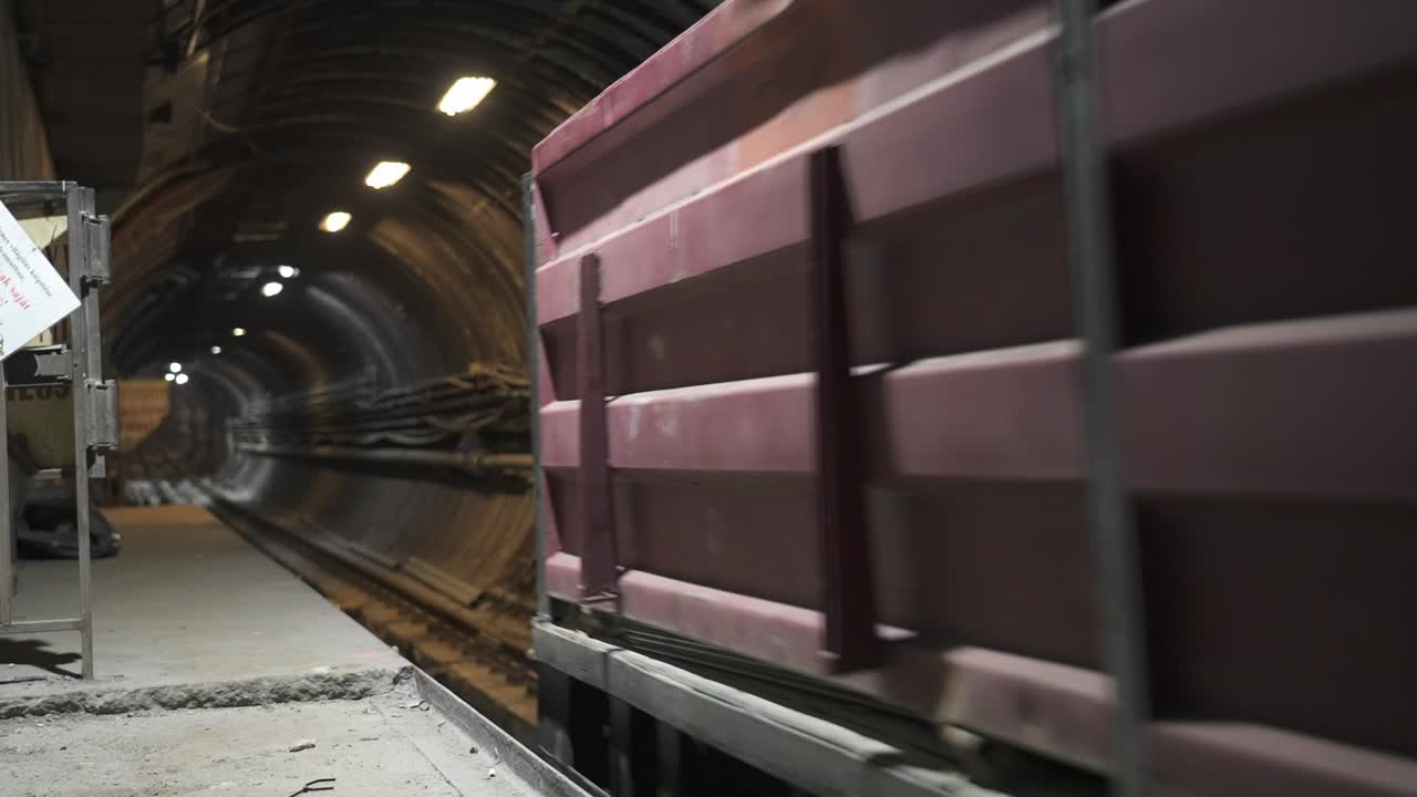 A red cargo wagon moving through a metro tunnel during ongoing renovation works