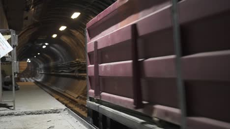 a red cargo wagon moving through a metro tunnel during ongoing renovation works