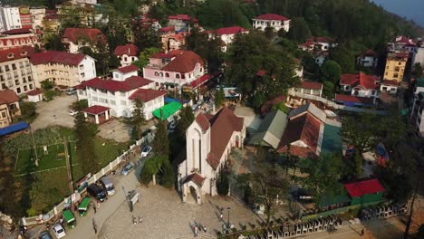 Una-Toma-Aérea-Descendente-Que-Se-Enfoca-En-La-Catedral-De-Notre-Dame-Revela-Una-Pequeña-Ciudad-Del-Sudeste-Asiático-En-Las-Montañas