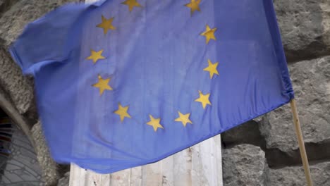 Ondeando-La-Bandera-De-La-Unión-Europea-Frente-A-La-Pared-De-Piedra-1