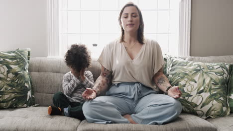 un niño pequeño y su madre meditando en un sofá