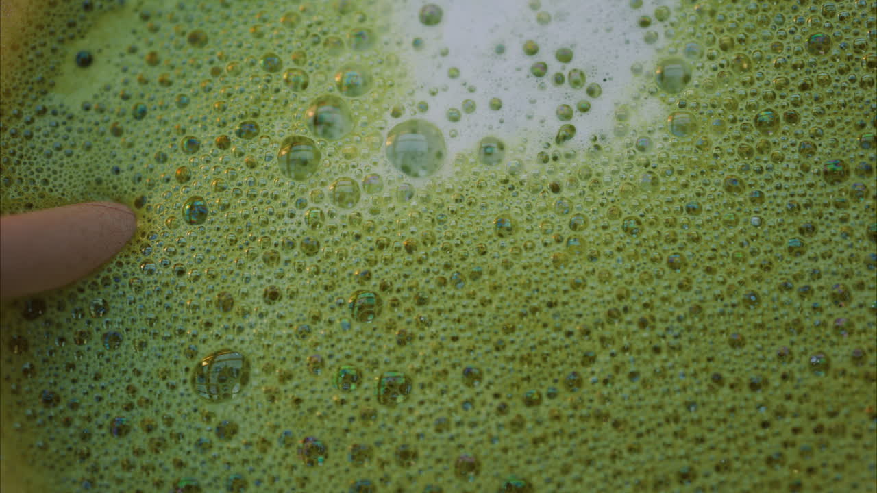 Close up of a matcha latte with a paper straw on a wooden table