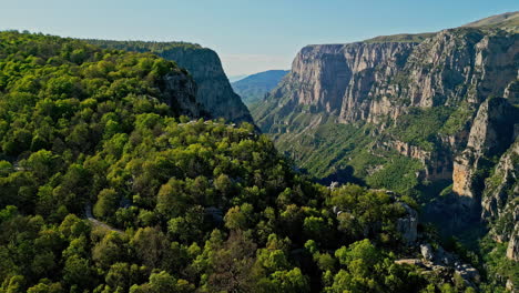 Vikos-Gorge-in-Greece-with-lush-green-forests-and-steep-cliffs,-beautiful-sunny-day,-aerial-view