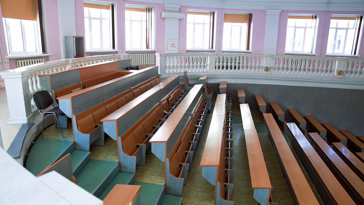 New auditorium for conference meeting. Empty lecture hall in the university during quarantine. Spacious classroom with rows of long desks for students to study.