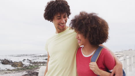 african american young couple smiling looking to each other while walking together on the promenade
