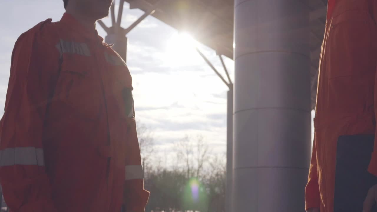 Closeup View Of Two Construction Workers In Orange Uniform And Hardhats Shaking Hands At The Bulding Object