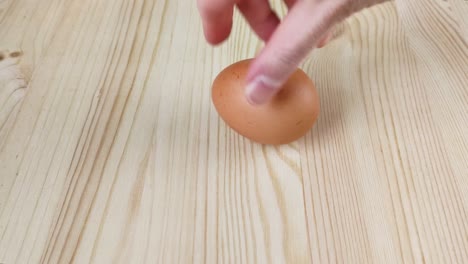 el huevo de pollo marrón gira en la mesa de madera
