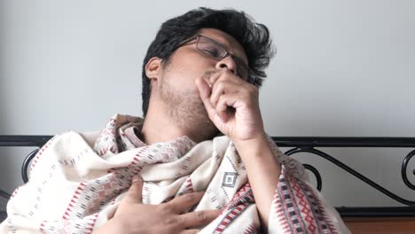 man wrapped in blanket, coughing