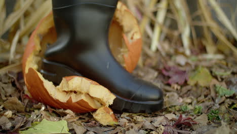 halloween jack-o'-lantern being stomped twice by a person wearing a black rubber boot