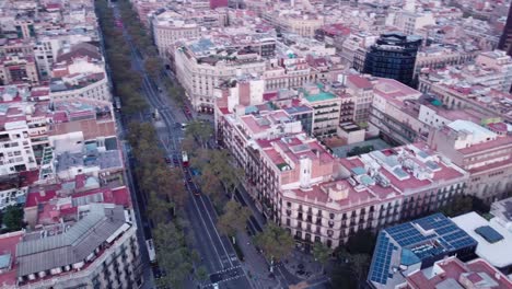 Barcelona-cityscape-with-roads-and-buildings-at-dusk,-hints-of-traffic,-aerial-view