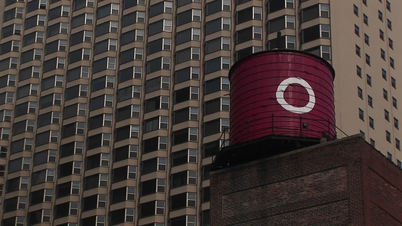 старомодная водонапорная башня с большой буквой "о" на ней находится на переднем плане снимка многоэтажного жилого дома".