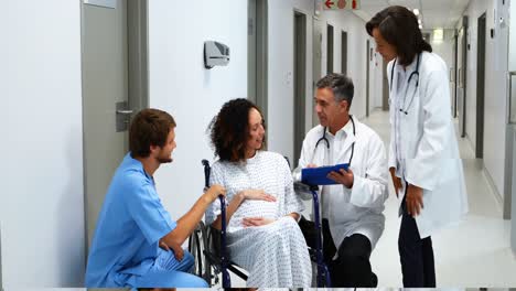 médicos interactuando con una mujer embarazada en el pasillo
